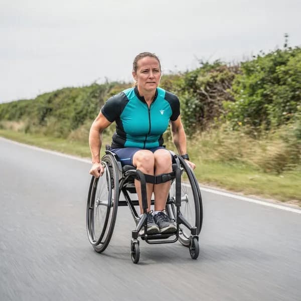 A woman racing on an open road in a racing wheelchair